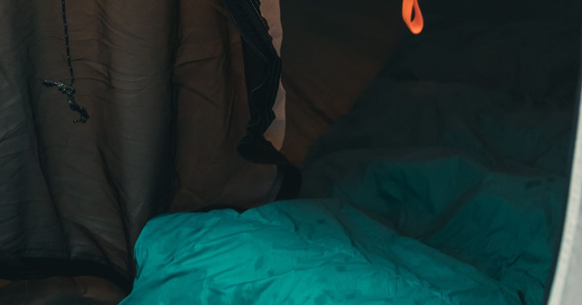 A down sleeping bag being stuffed into its compression sack.