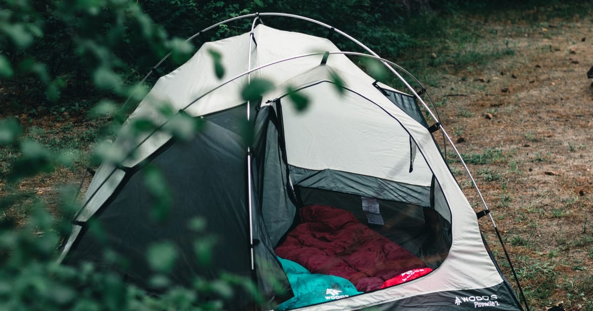 A sleeping bag laid out inside a tent at dusk.