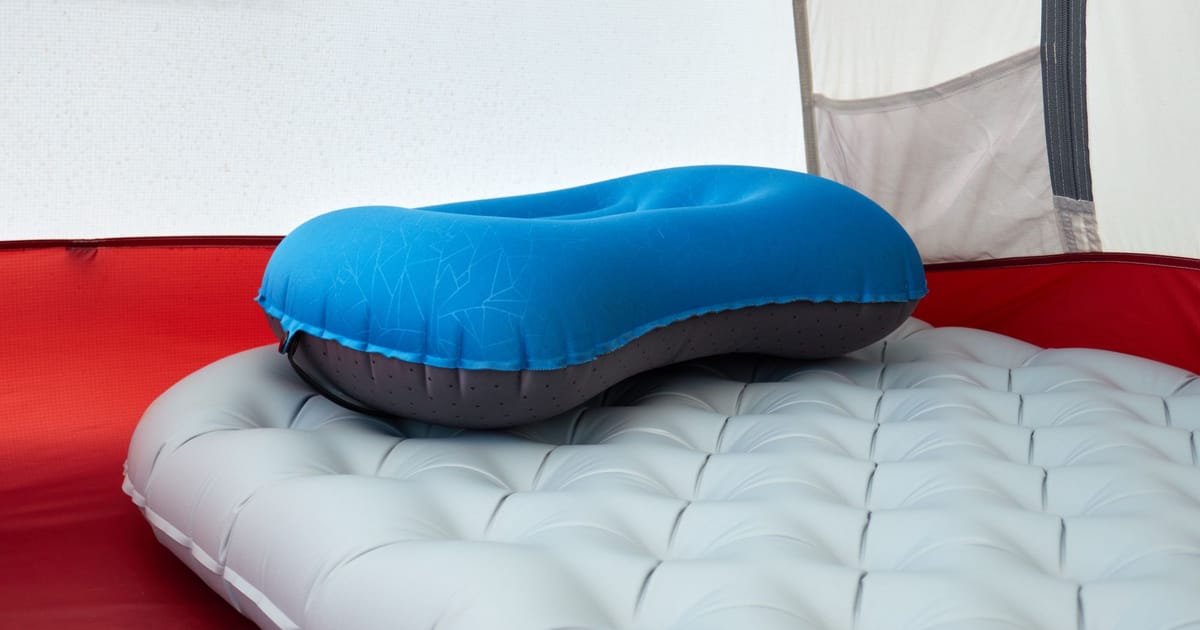 An inflatable sleeping mat unrolled on rocky ground.