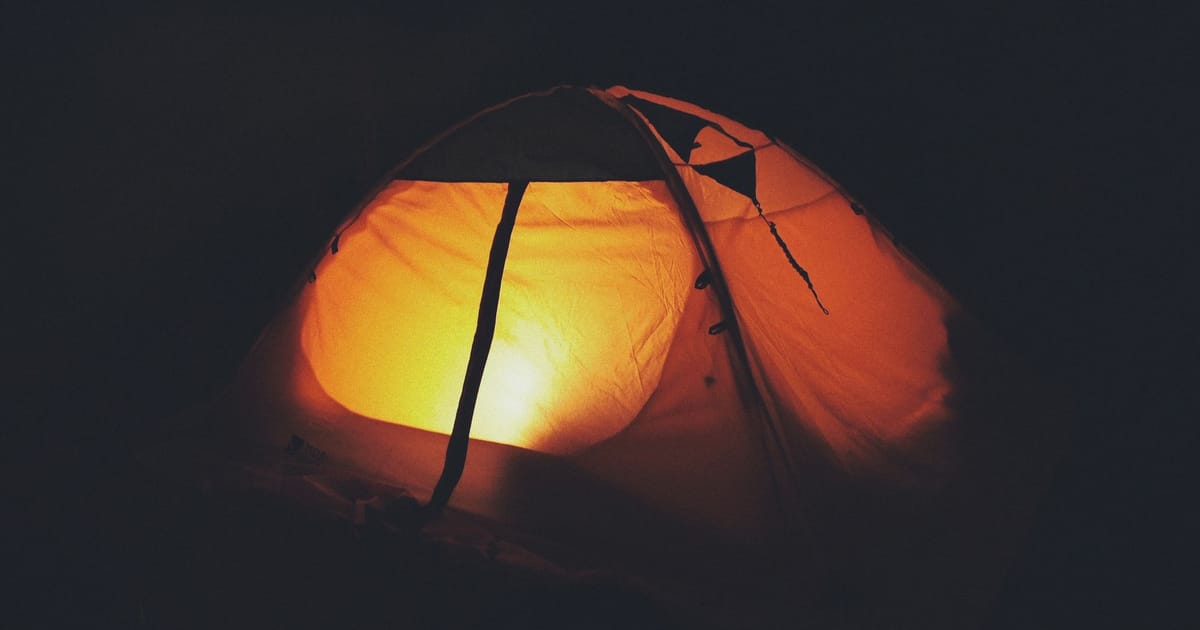 A tent glowing from a headtorch on a frosty night.