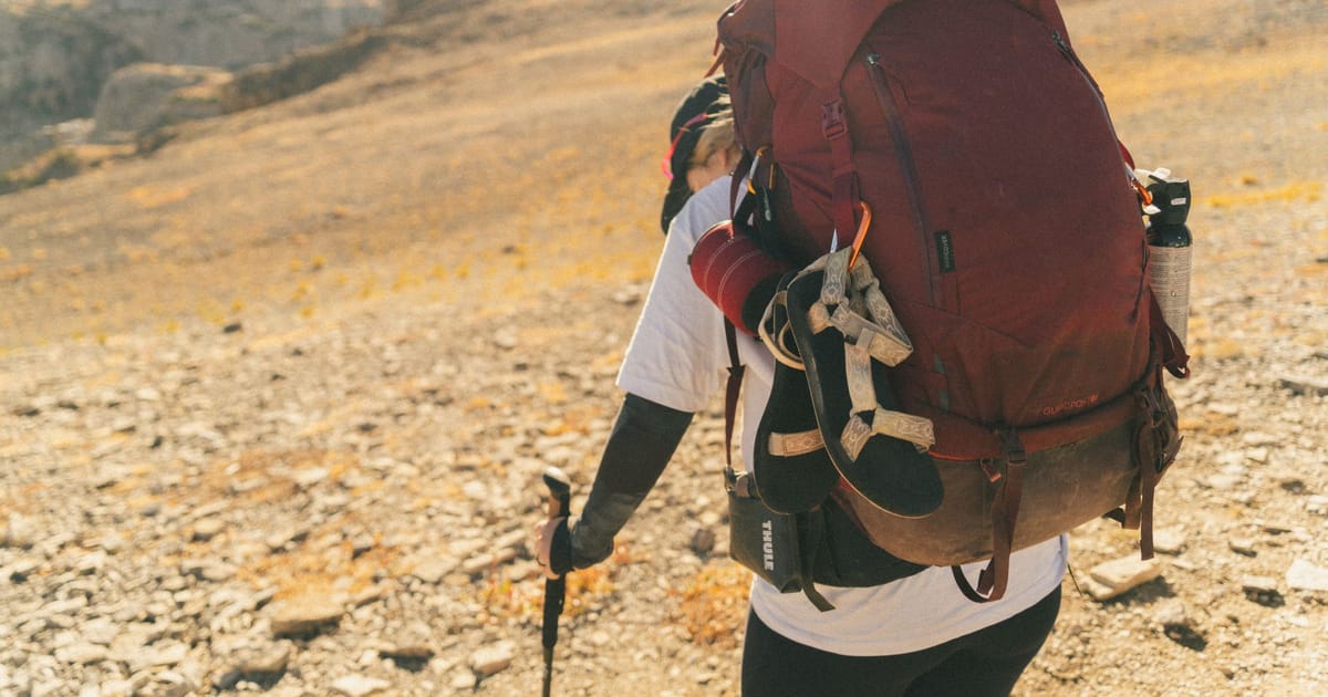 A walker adjusting the hip belt of a loaded backpack.